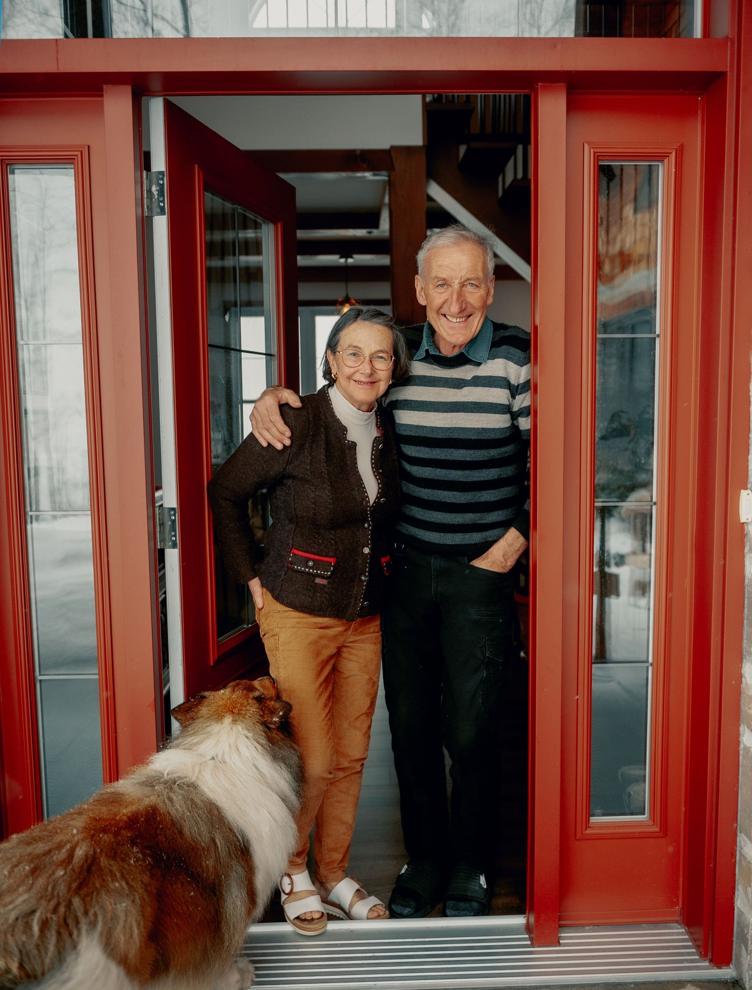 Laurence and Sebastian, hosts of The Alexandria Retreat, standing in a doorway with a dog at their feet, smiling.